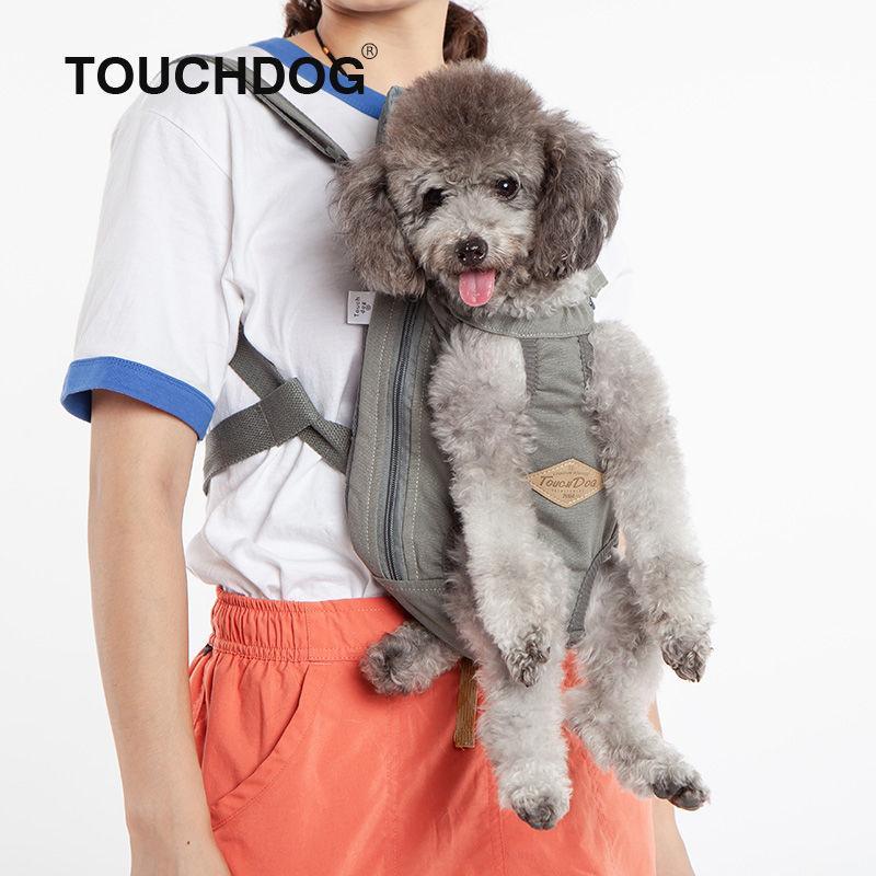 Person wearing a dog carrier with a small dog inside, branded 'TOUCHDOG'.