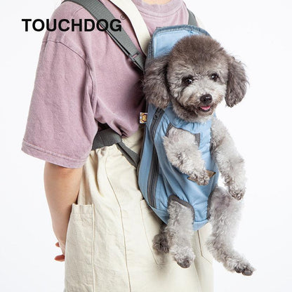 Person carrying a small dog in a blue pet carrier with 'TOUCHDOG' branding.