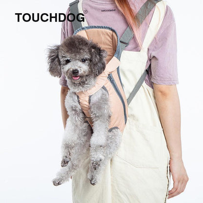 Small dog in a harness worn by a person with 'TOUCHDOG' branding